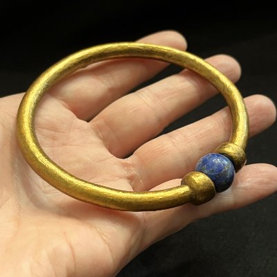 Flat perspective of the replica gold bracelet resting in a hand, displaying its circular form.