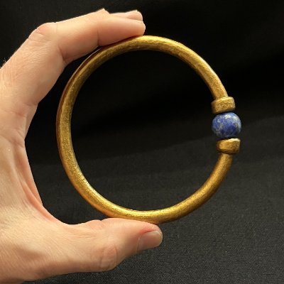 Upright view of the replica Egyptian bracelet held in a hand, illustrating its symmetrical design.
