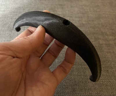 A top-down angled view of the bannerstone replica in a hand, highlighting the central perforation.