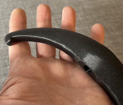 The black composite bannerstone replica rests across a palm to demonstrate its physical scale.