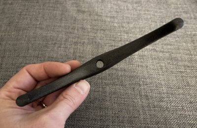 An edge-on perspective of the replica bannerstone in a hand, emphasizing its flat profile.