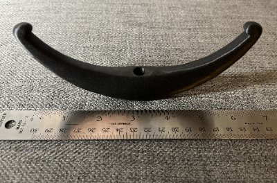 The bannerstone replica is measured against a steel ruler, confirming its 16-centimeter width.