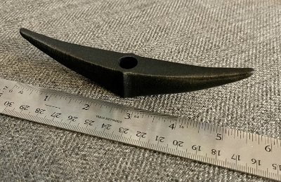The replica bannerstone positioned beside a ruler confirming its 13.6 centimeter length.