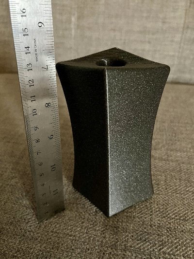 The 13.3-centimeter tall replica standing vertically next to a steel ruler.