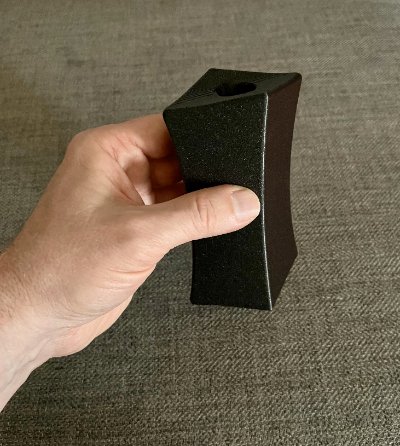 Angled view of the replica bannerstone held in a hand showing its curvature.