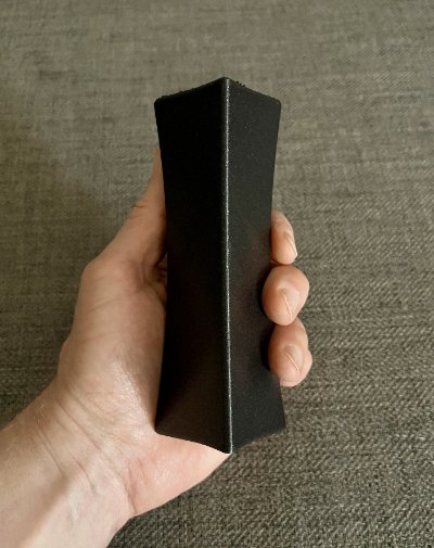 Side profile of the tall replica bannerstone held vertically in a hand.
