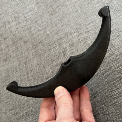 Vertical orientation in hand demonstrating the curvature and central perforation of the replica.
