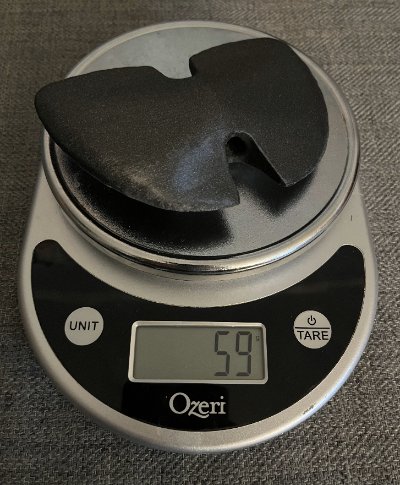 The bannerstone replica resting flat on a digital laboratory scale displaying exactly 59 grams.