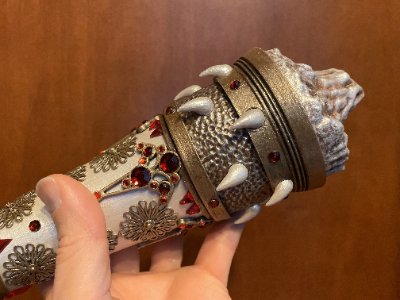 A hand holds the replica horn's base, revealing studded metal bands and textured sections.