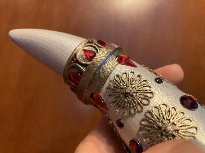 A hand holds the pointed tip of the replica horn, highlighting the upper jeweled metal band.