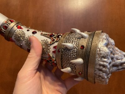 A hand grips the base of the Horn of Dagoth replica, showing the conical metal studs and jewels.