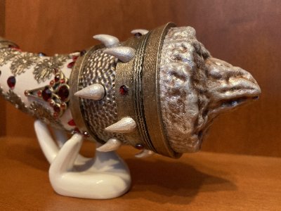 Close-up of the horn's textured base and studded metal collar resting on a white display stand.