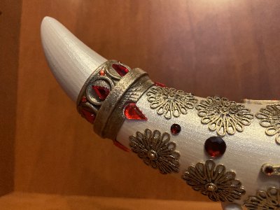 Close-up of the replica horn's curved tip featuring red rhinestone gems and brass filigree.