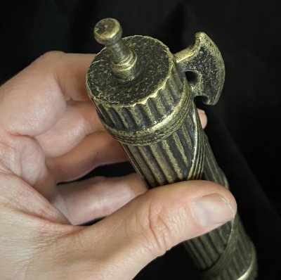Close-up of the axe blade and top bindings grasped by a hand.