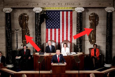 Wide view of the U.S. House chamber with arrows indicating the wall-mounted fasces.