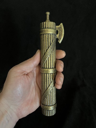 Hand holding the fasces replica vertically to demonstrate scale.