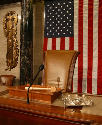 View of the Speaker's desk in the U.S. House chamber with the fasces on the wall.