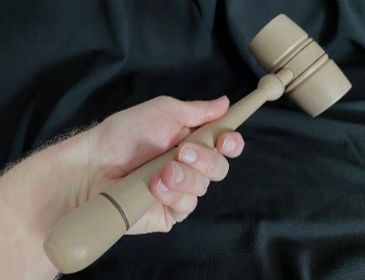 Forward-facing view of the replica gavel held in a hand showing the contoured handle grip design.
