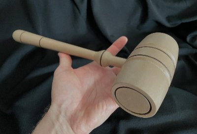 Leftward angled view of the replica gavel held in a hand to display its full length and proportion.