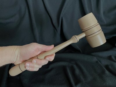 Rightward angled perspective of the replica gavel held in hand against a dark backdrop.