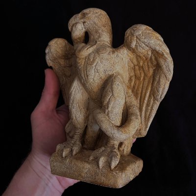 Full front view of the Roman eagle sculpture replica held by a human hand for scale.