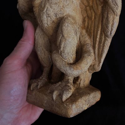 Close-up of the sculpture plinth and base being held, showing the lower coiling snake.