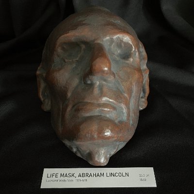 Direct frontal view of the reconstituted limestone Lincoln life mask and display tag.
