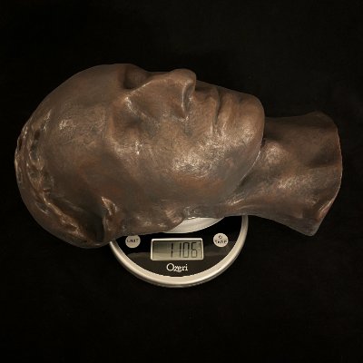 The reconstituted limestone and bronze replica resting flat upon a digital scale.