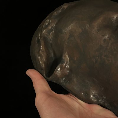 Detail of the flat back edge of the mask held in hand to show construction.