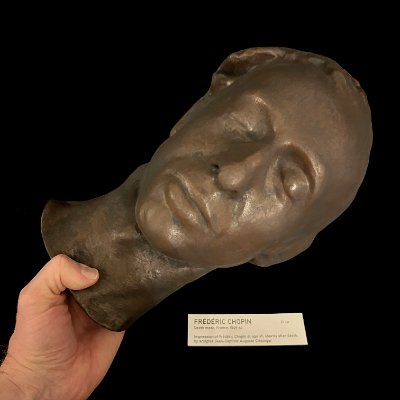 Frontal facial view of the replica held in hand to demonstrate scale.
