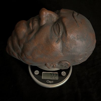 The bronze and limestone replica rests on a digital scale for mass measurement.