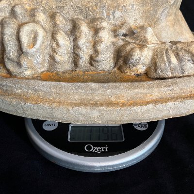 Detail of the limestone and bronze replica resting on a digital scale.