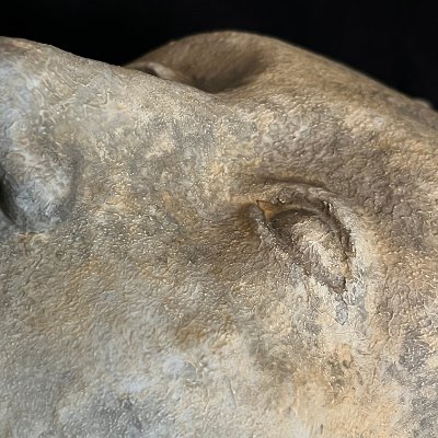 Extreme close-up of the left eye and brow ridge highlighting the patina.