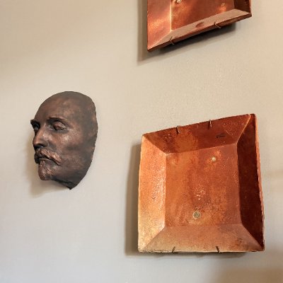 The Shakespeare mask replica mounted vertically on a light gallery wall.