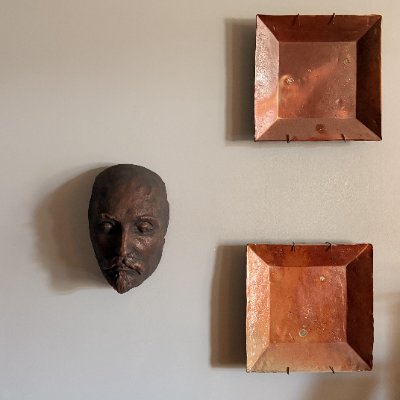 Frontal view of the Kesselstadt mask replica displayed on a white wall.