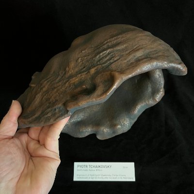 Profile edge view of the hollow mask held in hand to show the thickness of the casting.