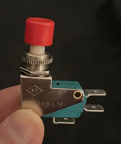 The uninstalled industrial-grade electrical momentary switch component with a red button cap.