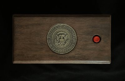 Overhead plan view of the Presidential call box with a central bronze seal and red button.