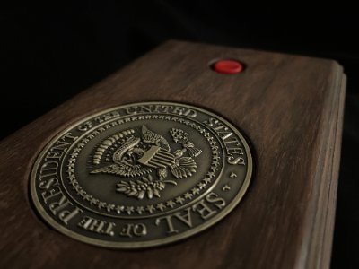 Low-angle isometric view showing the relief of the bronze seal and the wooden edge of the box.