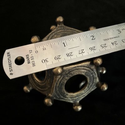 A metal ruler rests across the apex of the dodecahedron to verify its 10.5 centimeter width.