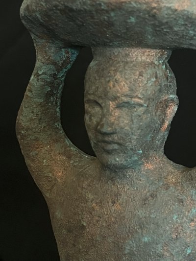 Right profile close-up detailing the facial features and textured patina.