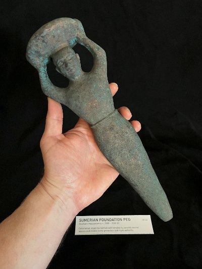 Angled view of the full peg replica resting across an open hand.