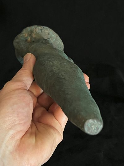 Close-up of the blunt, tapered lower point of the replica peg held in hand.