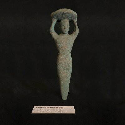 Full replica Sumerian foundation peg standing upright near museum tag.