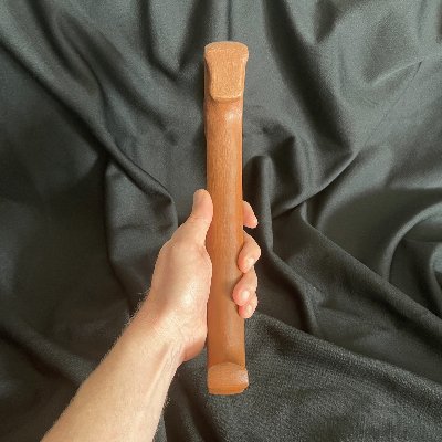 Vertical rear-edge view of the replica gavel held in a hand against a black background.