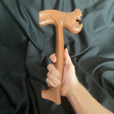 Right hand holding the wooden replica UN gavel upright to display the carved facial profile.