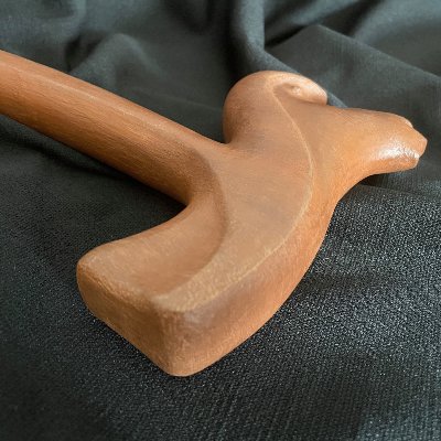 Detailed view of the replica gavel's carved head resting on a dark fabric background.