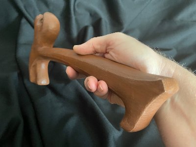 Hand supporting the replica gavel horizontally against a draped black textile background.