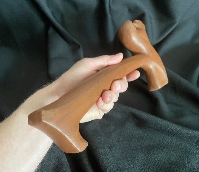 Hand holding the 30-centimeter wooden replica gavel horizontally to display its full length.