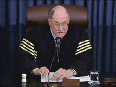 A broadcast frame captures Chief Justice Rehnquist at the Senate desk utilizing the handleless ivory gavel.